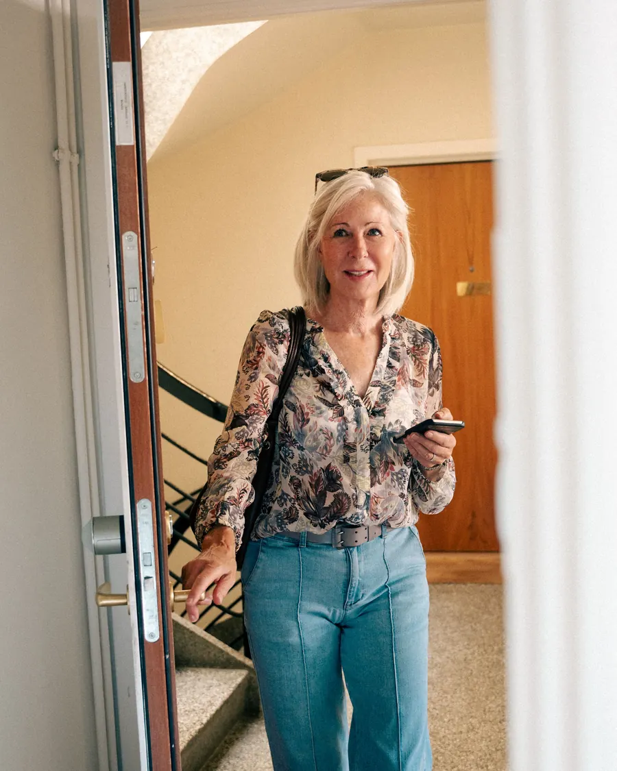 A resident leaves the flat with their phone in hand