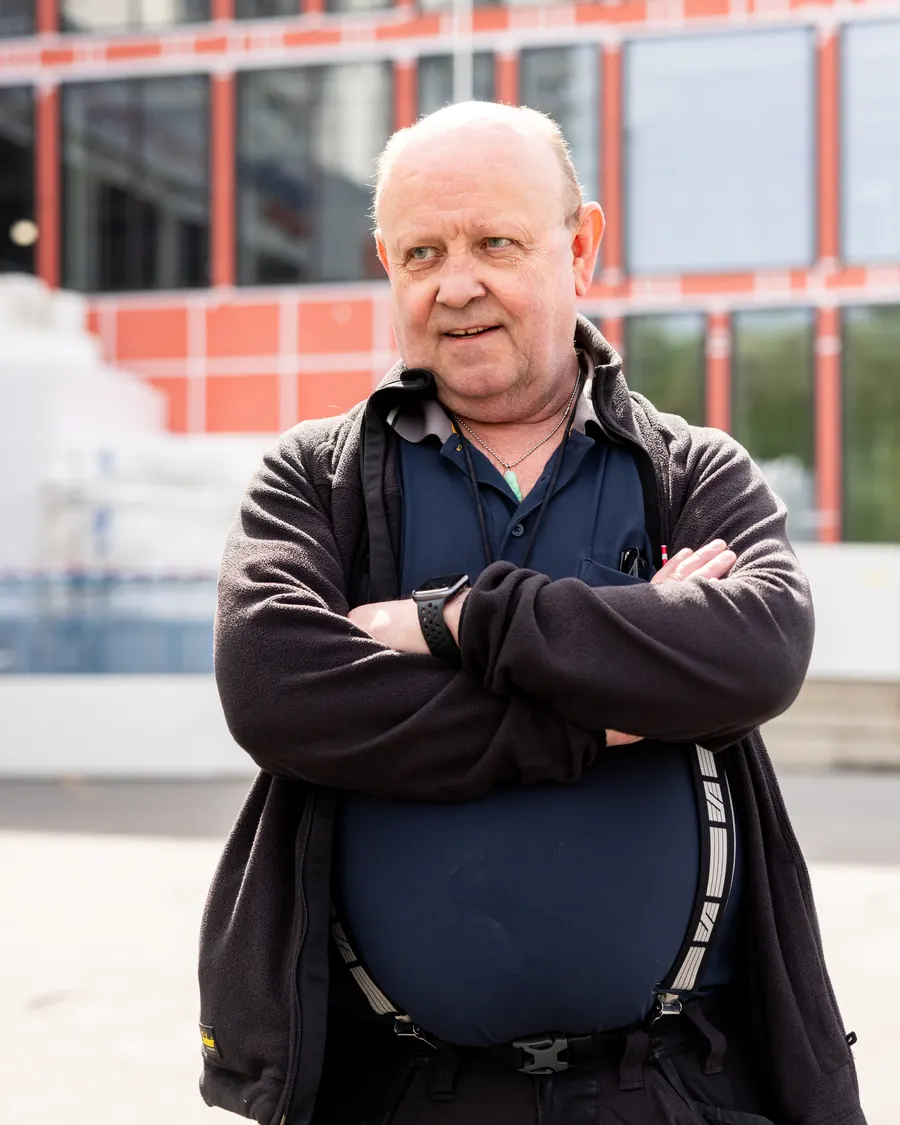 An operations technician at Ragde Eiendom in front of one of the buildings